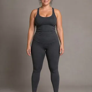 Full-length studio photo of a woman with an hourglass figure in a fitted charcoal tank top and leggings